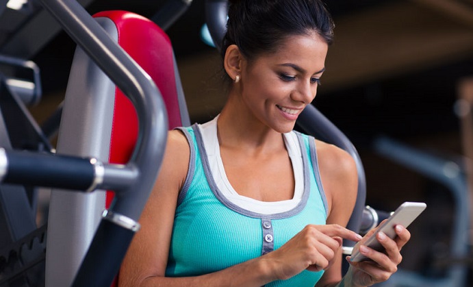 portrait of a happy fitness woman using smartphone in gym