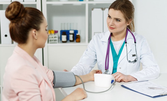 smiling cheerful female medicine doctor with pretty face measuring blood pressure to patient while chatting her. woman communicate with physician during medical examination. medical insurance concept