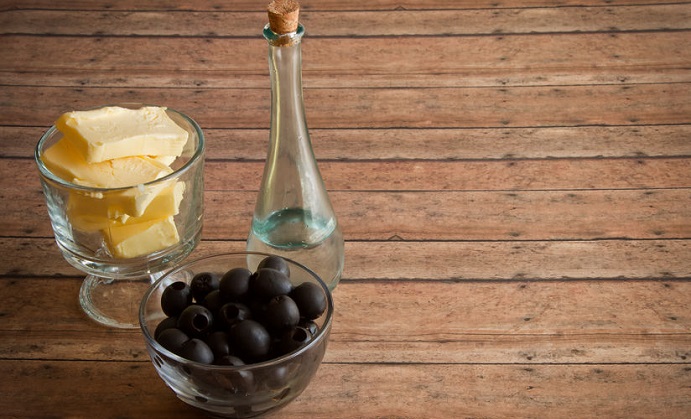 healthy fats of real butter, olives and mct and coconut oil for a ketogenic diet on a wood plank board